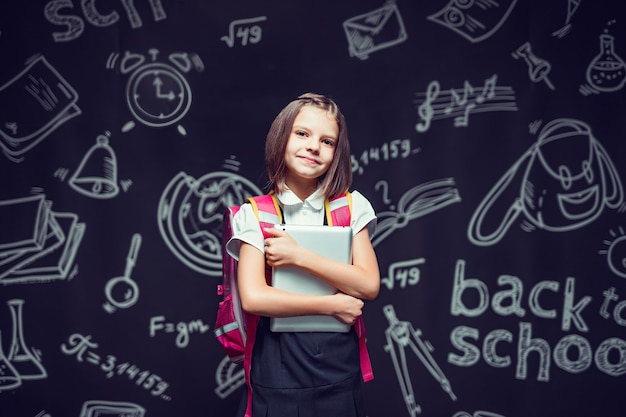 Allievo carino che si prepara per andare a scuola con zaino e tablet in mano per tornare al concetto di scuola