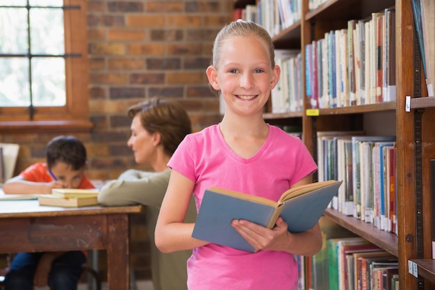 Cute pupil reading in library 