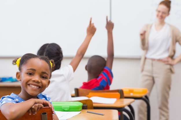 Cute pupil smiling at camera in classroom 