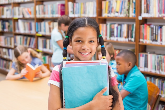 Cute pupil smiling at camera in library