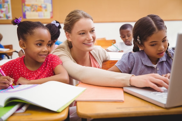 Photo cute pupil using computer with teacher