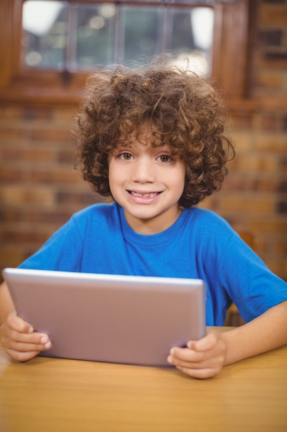 Cute pupil using tablet in the library