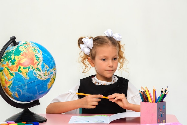 Cute pupil working at her desk on white background