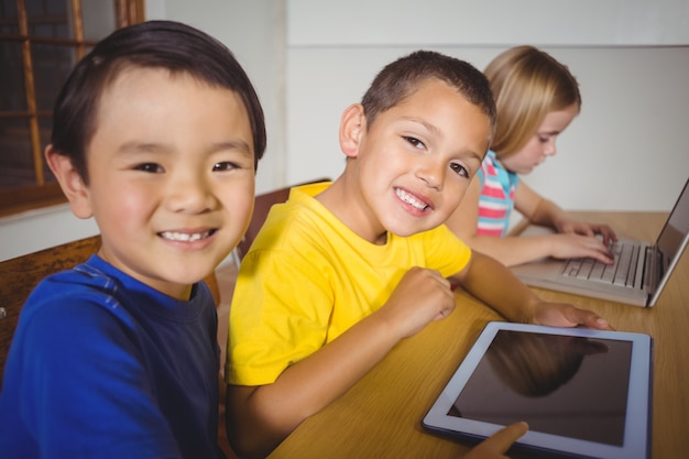 Cute pupils in class using laptop and tablet