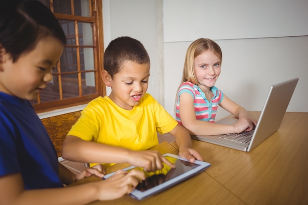 Cute pupils in class using laptop and tablet