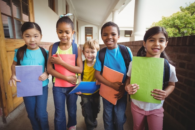 Cute pupils holding notebooks at corridor