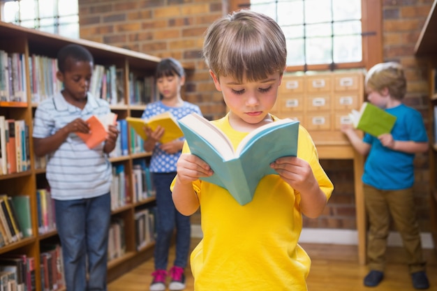 Cute pupils reading books at library 