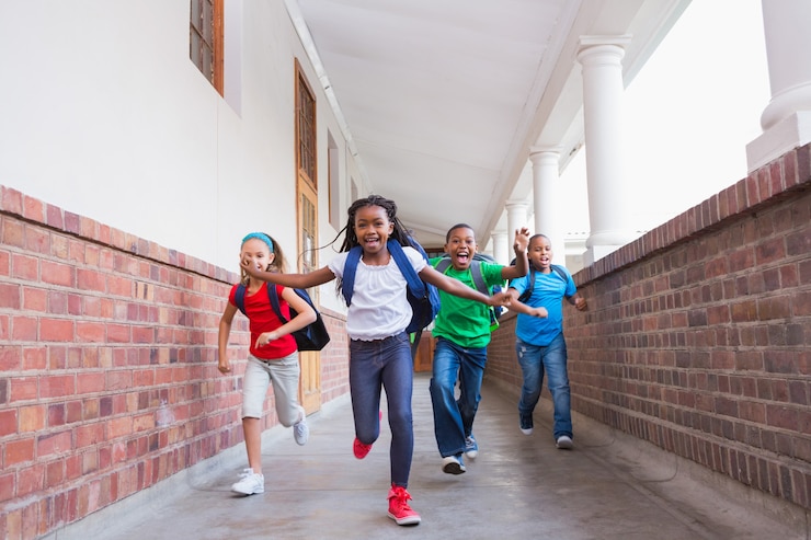 Photo cute pupils running and smiling at camera in hallway