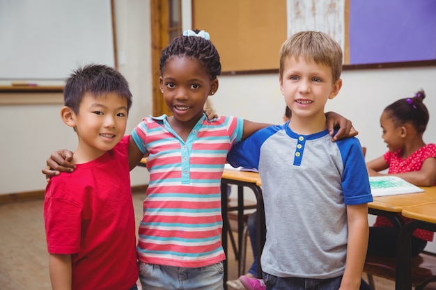 Cute pupils smiling at camera in classroom