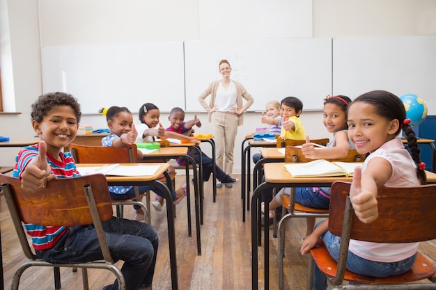 Cute pupils smiling at camera in classroom 