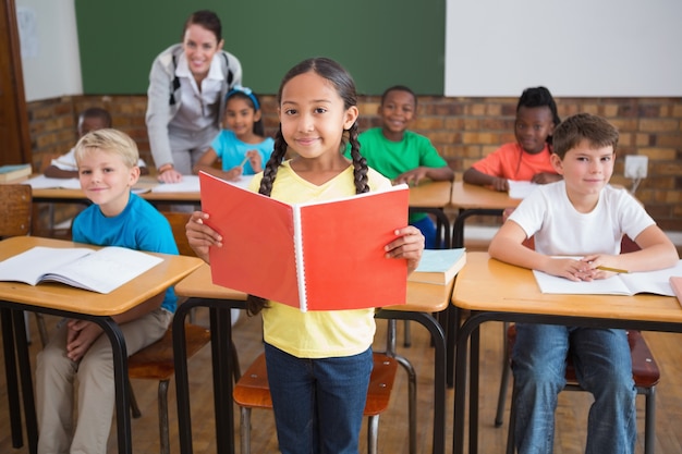 Cute pupils smiling at camera in classroom