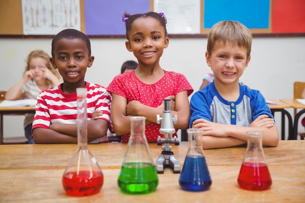 Cute pupils standing with arms crossed behind beaker