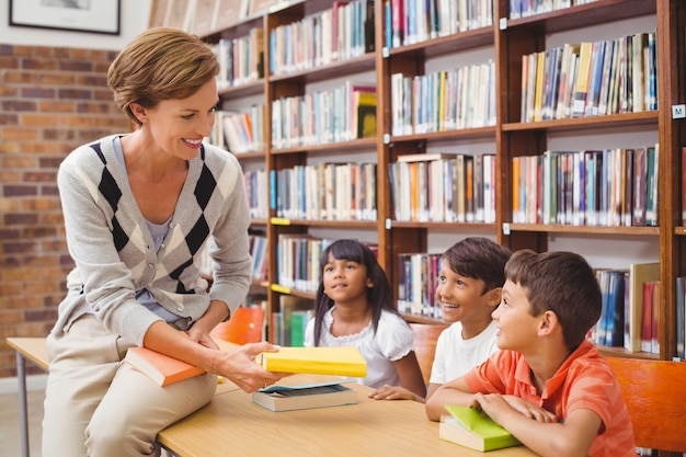 Cute pupils and teacher looking for books in library