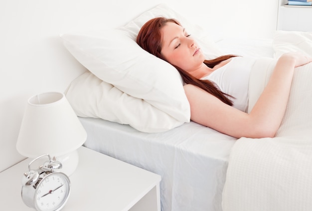 Cute red-haired female having a rest while lying on her bed