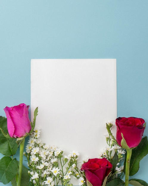 Photo cute red and pink roses on light blue background with paper frame space