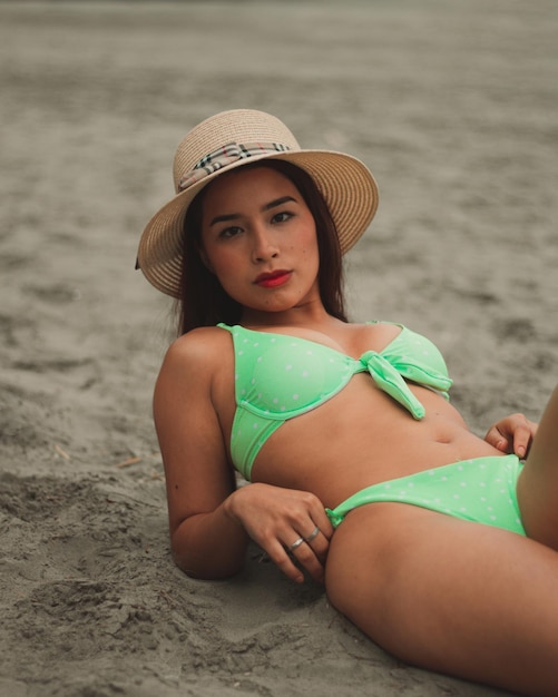 Симпатичная рыжеволосая девушка с восточными чертами лица в шляпе на пляже