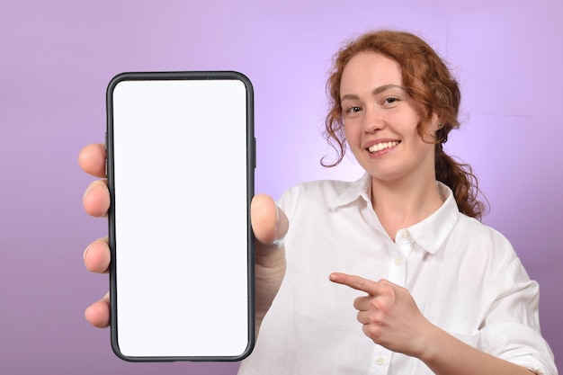 cute redhead curly woman holding phone with blank white screen