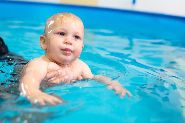어린 아이들을 위한 특별 수영장에서 수영을 배우는 귀여운 슬픈 아기