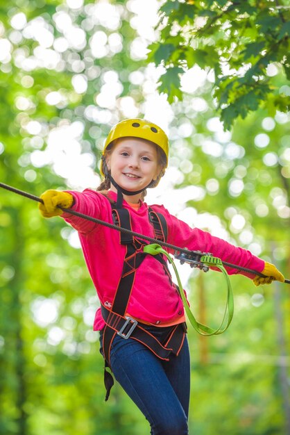 Cute school child boy enjoying a sunny day in a climbing adventure activity park Artworks depict games at eco resort which includes flying fox or spider net