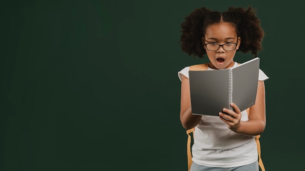 Foto ragazza carina della scuola che legge i suoi appunti