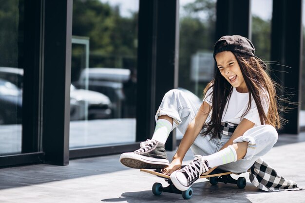 Cute school girl with skate board in the street