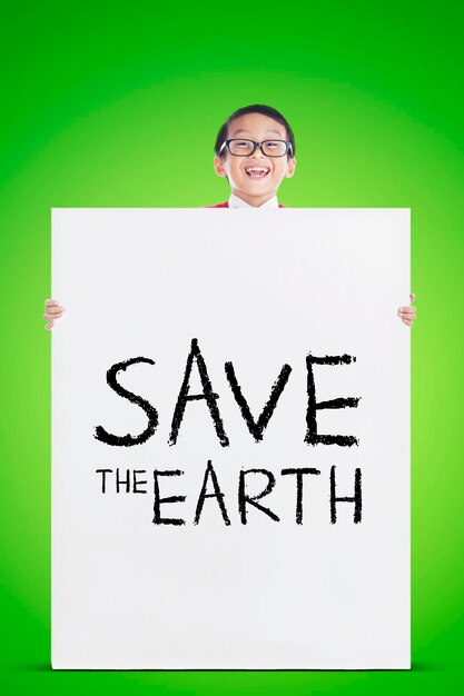 Photo cute schoolboy showing text of save the earth