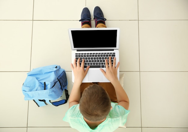 Photo cute schoolboy with laptop, top view