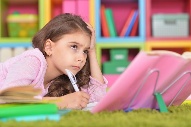 Cute schoolgirl doing homework at her room