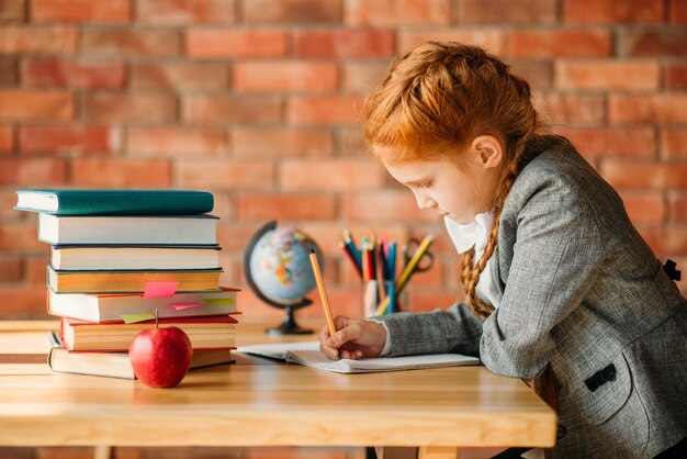 Cute schoolgirl doing homework at the table