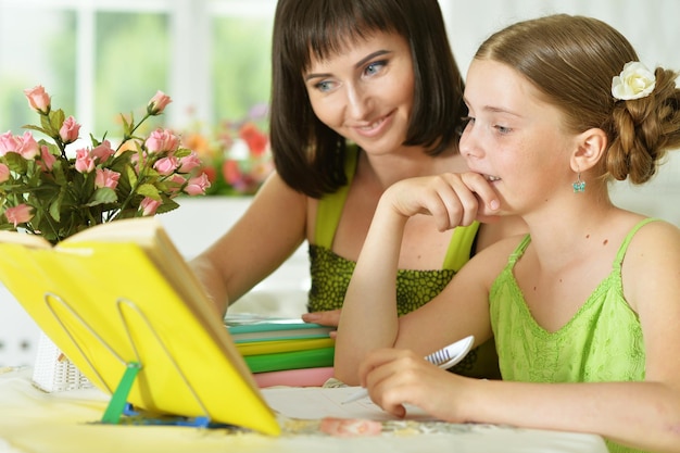 Cute schoolgirl doing homework with her mother at home