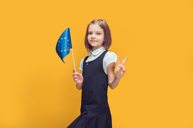 Cute schoolgirl with the flag of european union raising index finger up education in europe concept