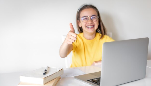 Photo cute schoolgirl with a laptop studying at home online learning