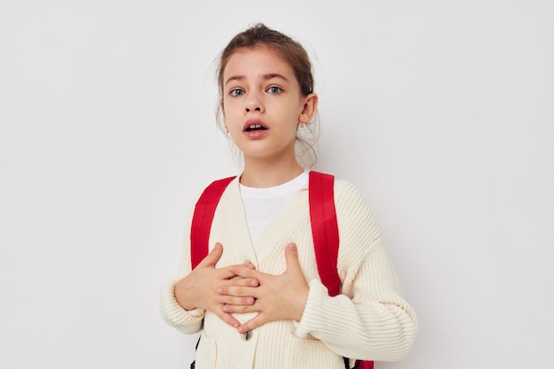 Cute schoolgirl with red backpack posing isolated background