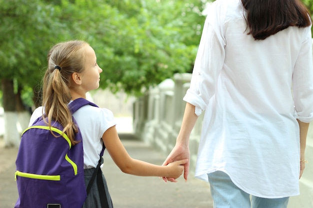 校庭で学校のバックパックを持つかわいい女子高生