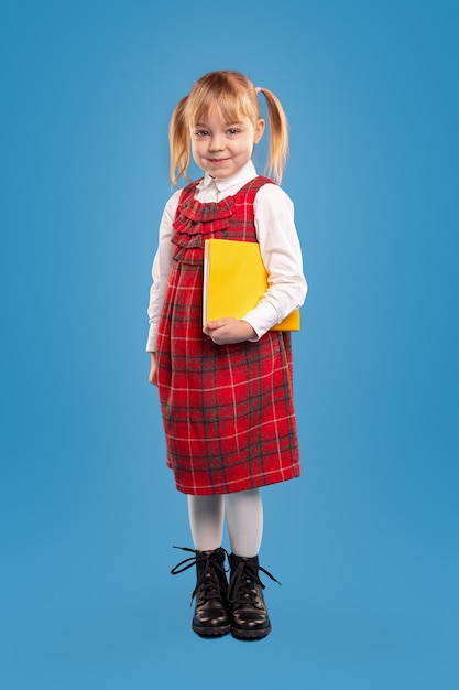 Cute schoolgirl with textbook smiling