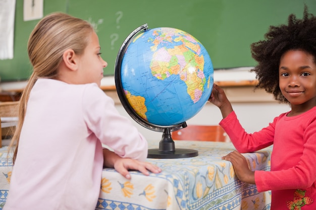 Cute schoolgirls looking at a globe