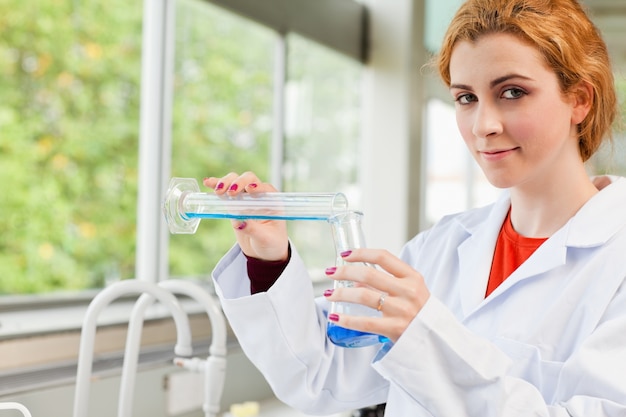 Cute scientist pouring liquid