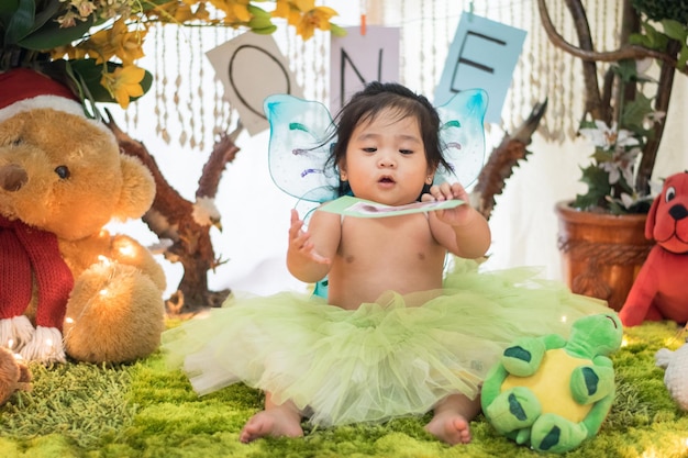 Cute shirtless baby girl sitting amidst stuffed toys during birthday