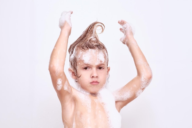 Cute shirtless boy covered with foam with wet hair in mohawk looking at camera isolated on white background during daily routine