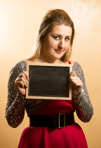 Photo cute shy woman posing with empty blackboard