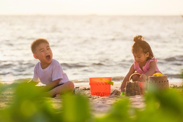 Photo cute sibling playing on beach against sky