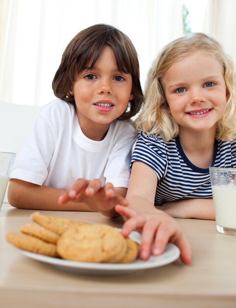 Photo cute siblings eating biscuits