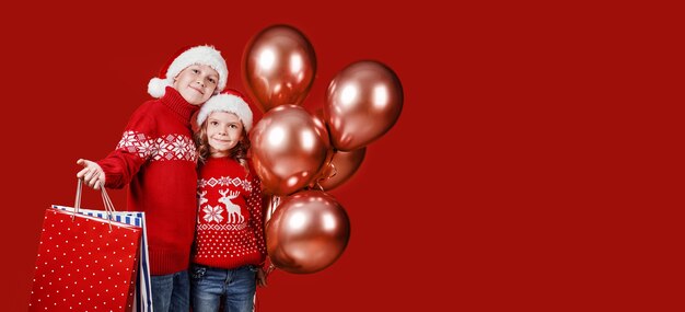 Cute siblings in red sweater holding shopping bags