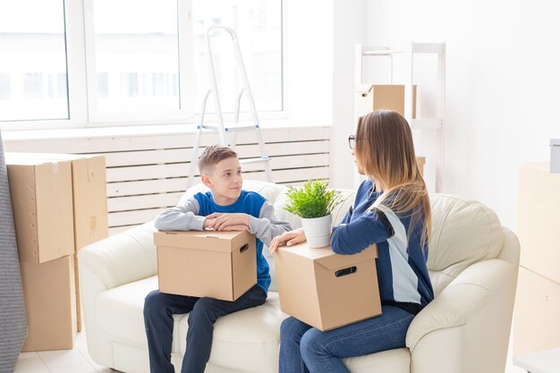 Cute single mom and little boy son sort boxes with things after the move. The concept of