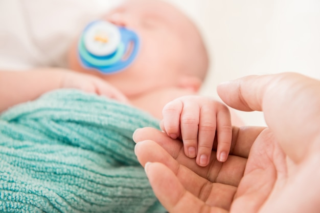 Cute sleeping baby holding hand of father