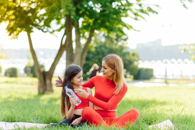 Cute smal daughter and mother do exerciese, fitness, yoga in morning park