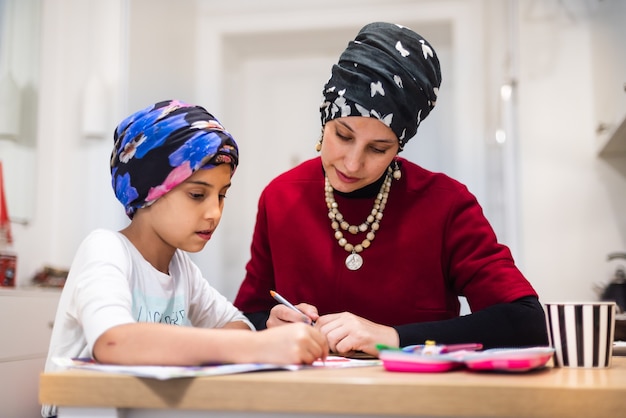 Cute small 6-7 years kid daughter learning writing with young mom tutor