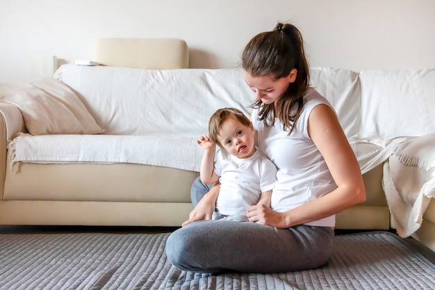 Cute small boy with Down syndrome playing with mother in home