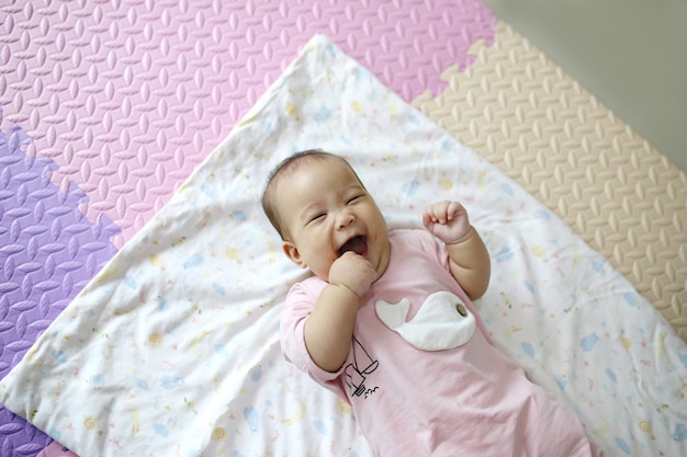 Cute smart Asian newborn baby sleeping with teddy rabbit toy on pink soft bed at home.