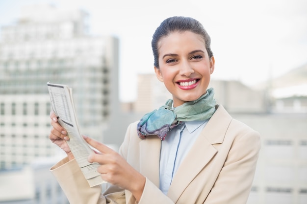 Cute smart brown haired businesswoman holding a newspaper